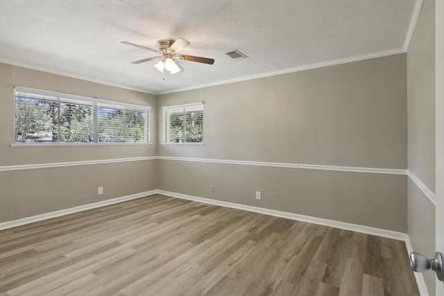 empty room with ceiling fan, wood-type flooring, a textured ceiling, and ornamental molding