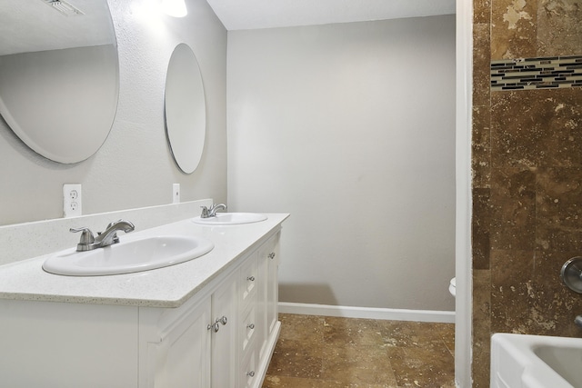 bathroom with a washtub, vanity, and toilet