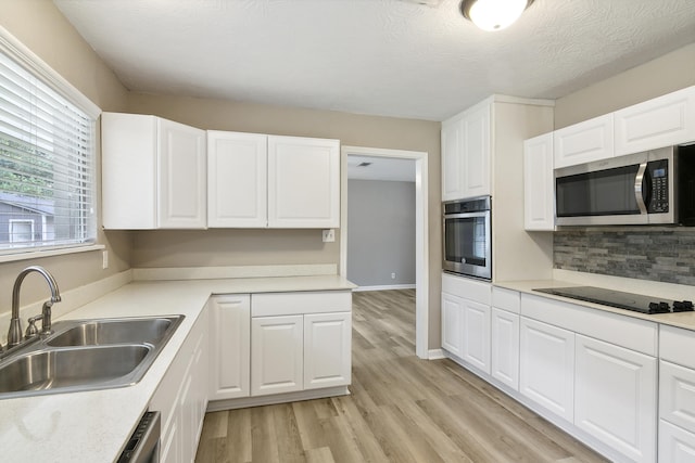 kitchen with sink, stainless steel appliances, backsplash, light hardwood / wood-style floors, and white cabinets