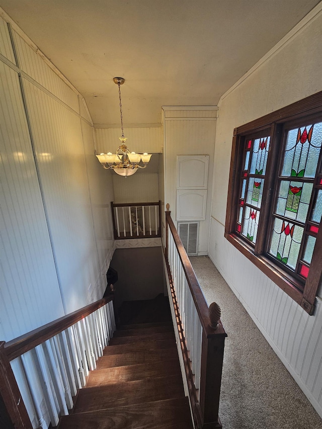 stairway with carpet and a notable chandelier