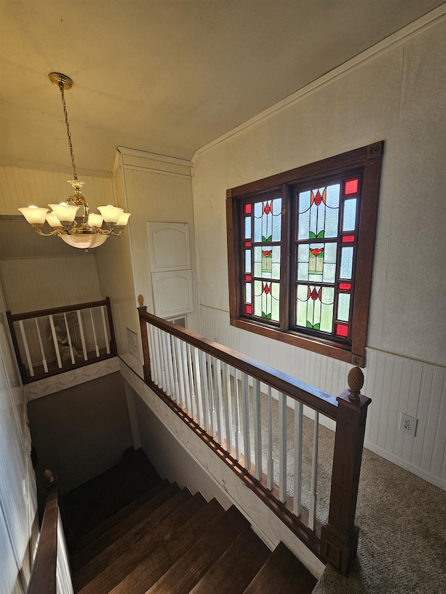 staircase with a chandelier and carpet flooring