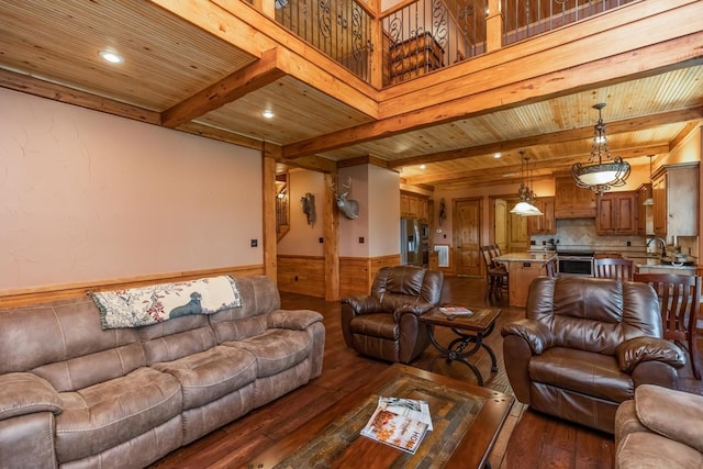 living room featuring beam ceiling, dark hardwood / wood-style flooring, wooden ceiling, and sink