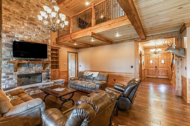 living room with beamed ceiling, a chandelier, a fireplace, and wood ceiling