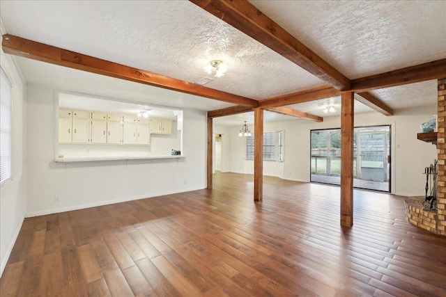 unfurnished living room with beamed ceiling, wood-type flooring, and a textured ceiling