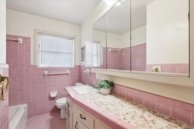 full bathroom with tile walls, tile patterned flooring, vanity, tiled shower / bath combo, and toilet