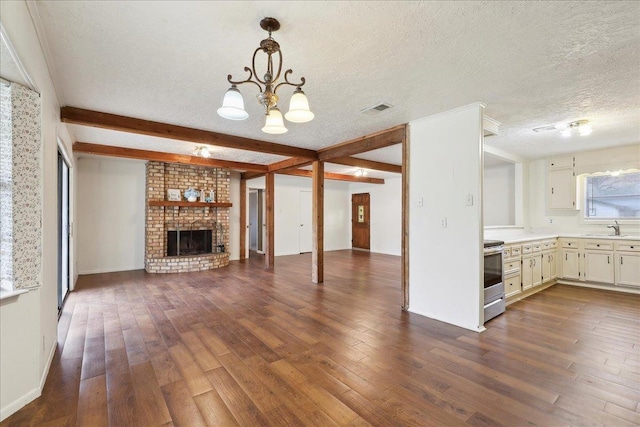 unfurnished living room featuring a fireplace, beamed ceiling, sink, dark wood-type flooring, and a textured ceiling