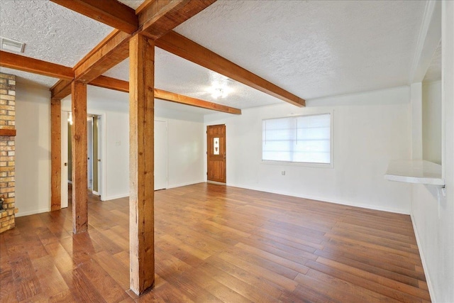 unfurnished living room with hardwood / wood-style floors, beam ceiling, and a textured ceiling