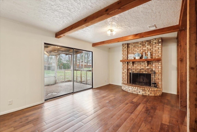 unfurnished living room with hardwood / wood-style flooring, a fireplace, a textured ceiling, and beamed ceiling