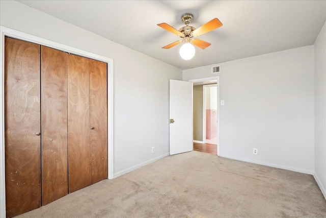 unfurnished bedroom featuring ceiling fan, light colored carpet, and a closet