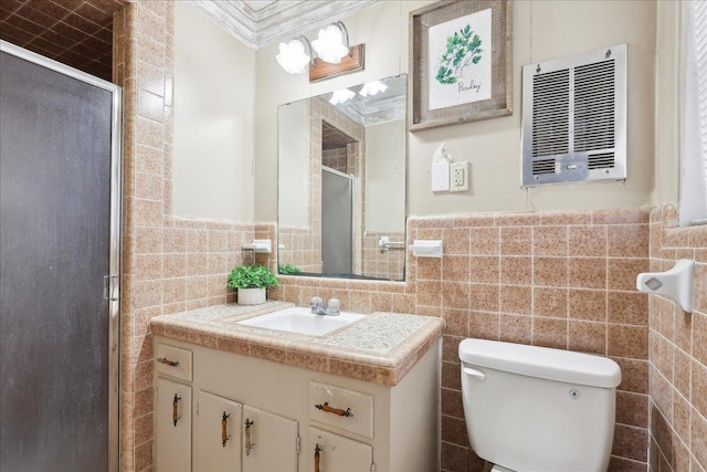 bathroom featuring vanity, toilet, a shower with door, and tile walls