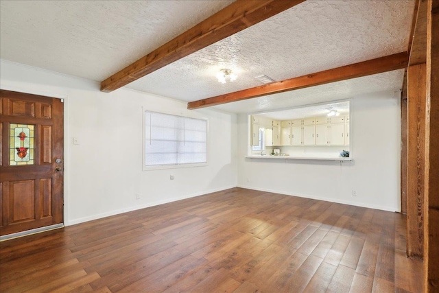 unfurnished living room with beamed ceiling, a textured ceiling, and hardwood / wood-style flooring