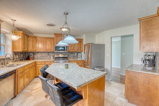 kitchen with a breakfast bar, decorative light fixtures, sink, and appliances with stainless steel finishes