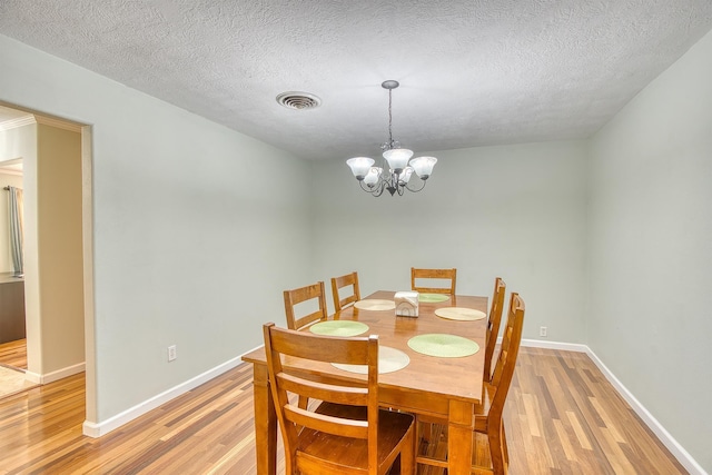 dining space with a textured ceiling, hardwood / wood-style flooring, and a notable chandelier