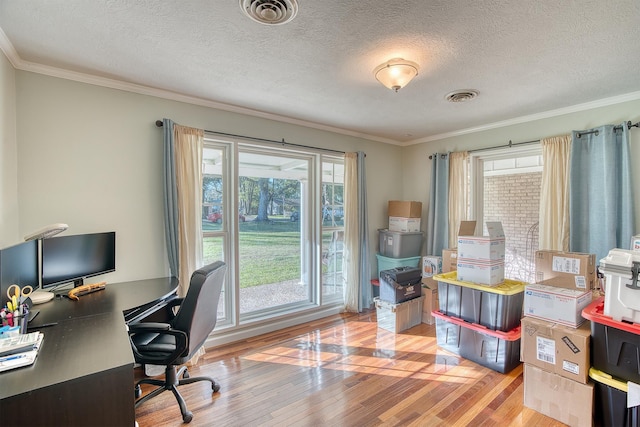 office featuring a textured ceiling, light wood-type flooring, a wealth of natural light, and crown molding