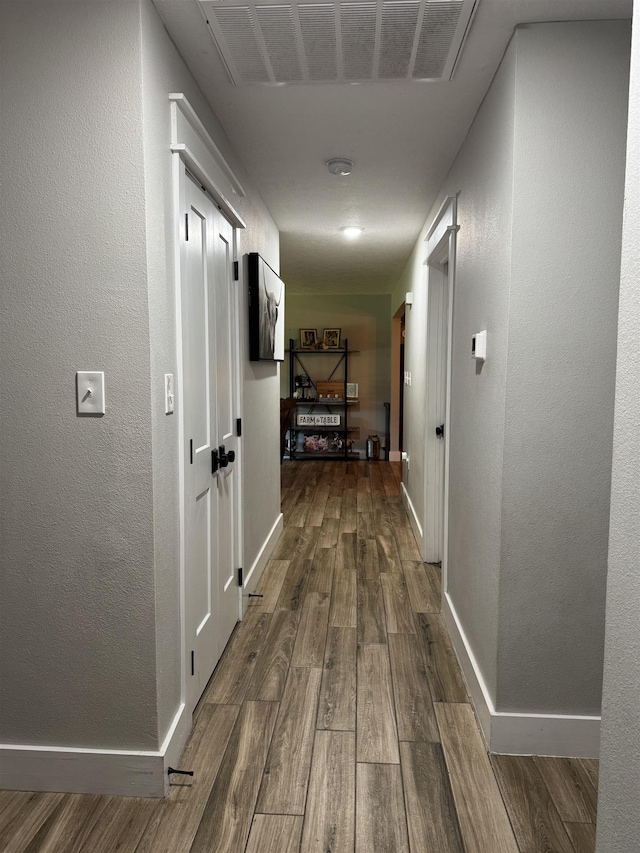 hallway with visible vents, dark wood-style floors, and baseboards