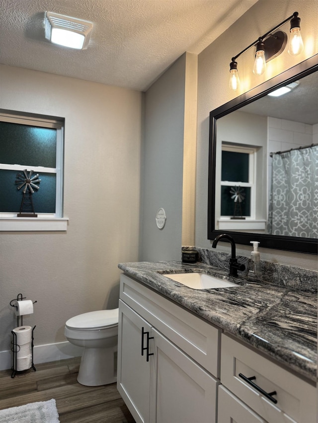bathroom featuring vanity, toilet, a textured ceiling, wood finished floors, and a shower with shower curtain