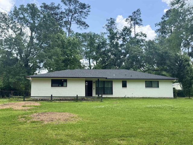 rear view of property featuring brick siding, fence, and a yard