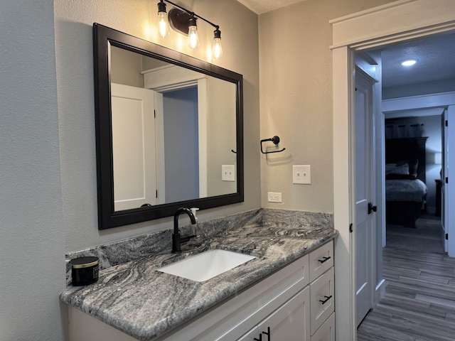 bathroom with vanity, a textured wall, and wood finished floors