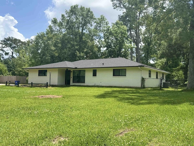rear view of house featuring fence, a yard, and brick siding