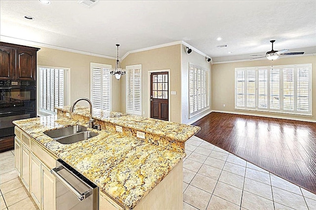 kitchen with crown molding, light tile patterned floors, stainless steel dishwasher, sink, and an island with sink