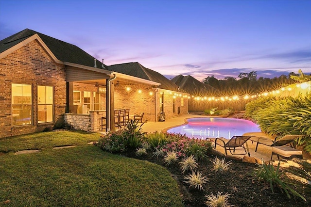 pool at dusk featuring a patio area and a yard