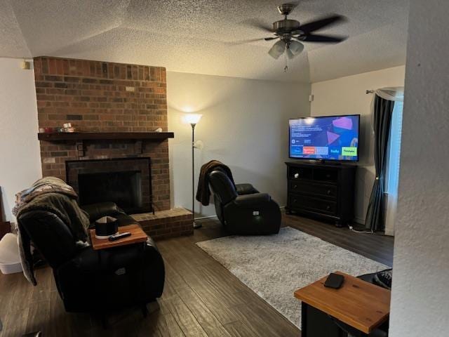 living room with a fireplace, ceiling fan, dark hardwood / wood-style flooring, and a textured ceiling