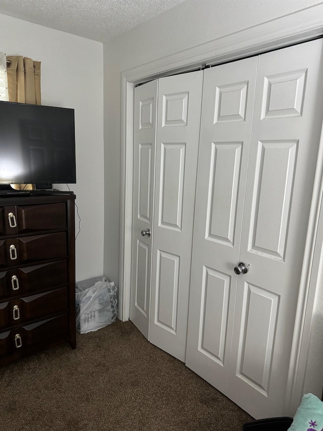 bedroom featuring dark carpet, a textured ceiling, and a closet