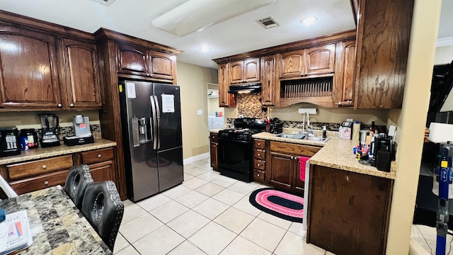 kitchen featuring black appliances, dark brown cabinetry, light tile patterned floors, and sink