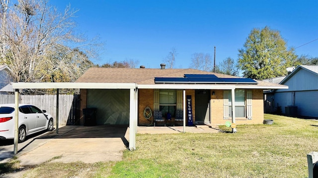 view of front of property featuring a carport, solar panels, central AC, and a front lawn