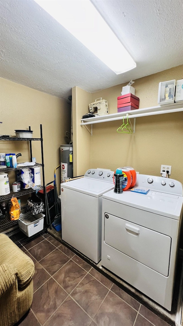 laundry area with gas water heater, dark tile patterned floors, a textured ceiling, and independent washer and dryer