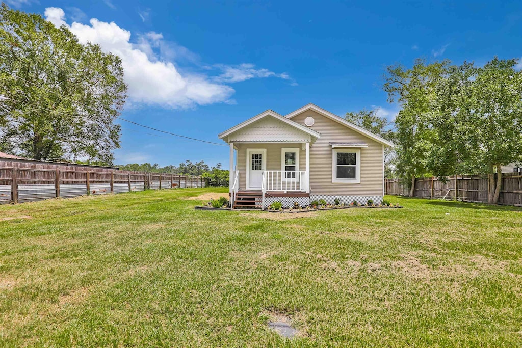 rear view of property with covered porch and a yard