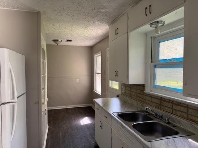 6 Circle Q St, Orange, TX 77630 - kitchen with freestanding refrigerator, a sink, a textured ceiling, white cabinetry, and baseboards