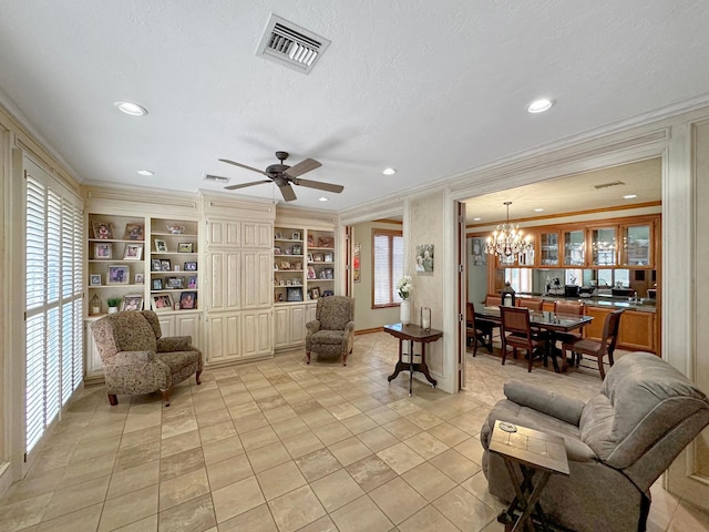 living room with a textured ceiling, built in shelves, crown molding, and ceiling fan with notable chandelier