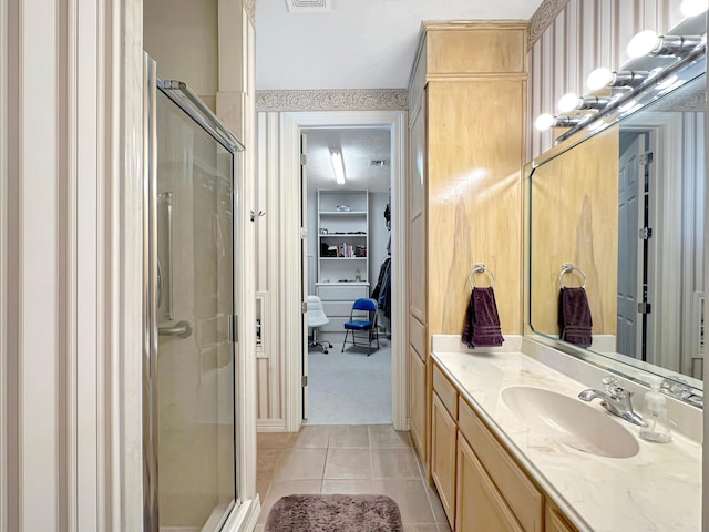 bathroom with tile patterned floors, a shower with door, and vanity