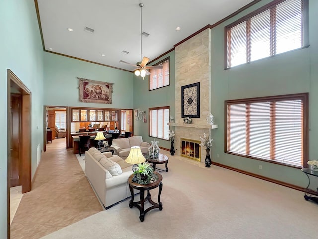 living room featuring ceiling fan, a healthy amount of sunlight, a premium fireplace, and a high ceiling