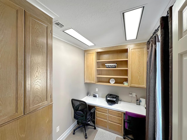 home office featuring light colored carpet, built in desk, and a textured ceiling