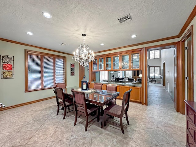 tiled dining space with a chandelier, a textured ceiling, and crown molding