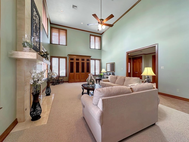 living room with ceiling fan, crown molding, light colored carpet, and a high ceiling