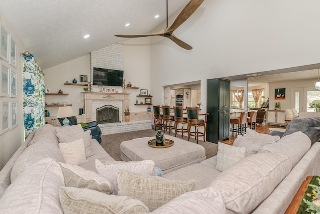 living area with a ceiling fan, a textured ceiling, a fireplace, high vaulted ceiling, and recessed lighting