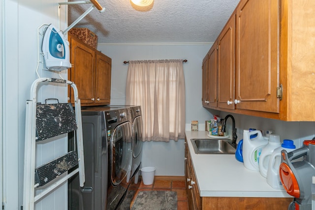 laundry area featuring cabinet space, a sink, washer and clothes dryer, and a textured ceiling