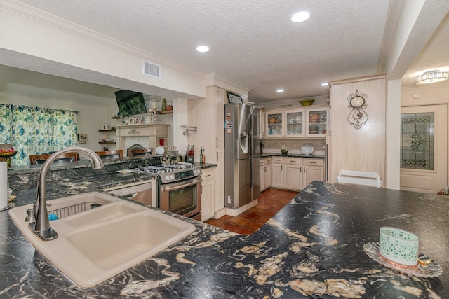 kitchen with visible vents, glass insert cabinets, appliances with stainless steel finishes, a peninsula, and a sink