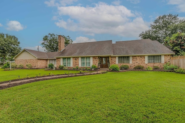 ranch-style house with a chimney, roof with shingles, fence, a front yard, and brick siding