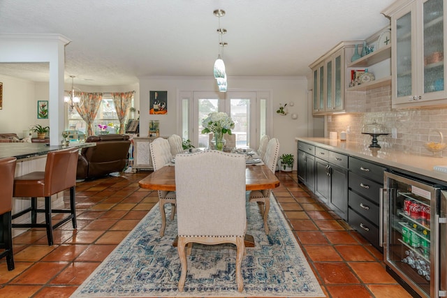 dining room featuring beverage cooler, plenty of natural light, a notable chandelier, and crown molding