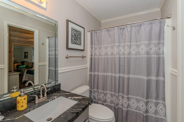 bathroom featuring ornamental molding, wainscoting, vanity, and toilet