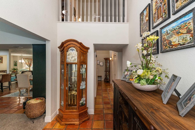 entrance foyer featuring dark tile patterned floors, a towering ceiling, baseboards, and an inviting chandelier