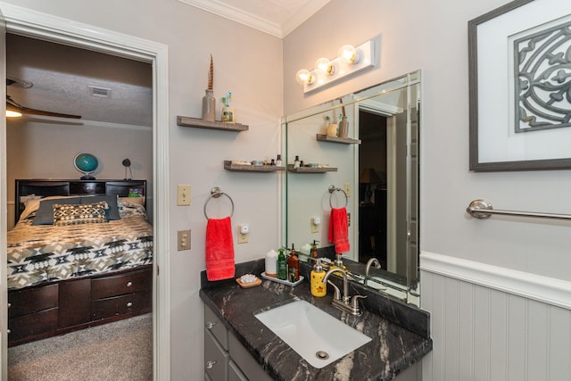 bathroom with a wainscoted wall, crown molding, visible vents, vanity, and ensuite bath