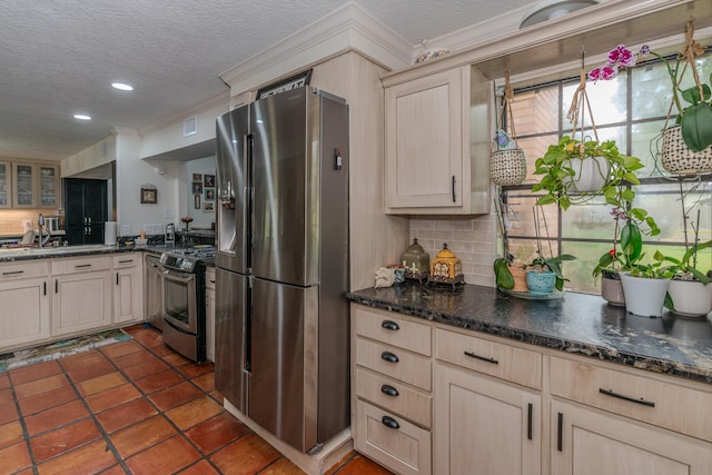 kitchen featuring tasteful backsplash, appliances with stainless steel finishes, a textured ceiling, light brown cabinetry, and a sink