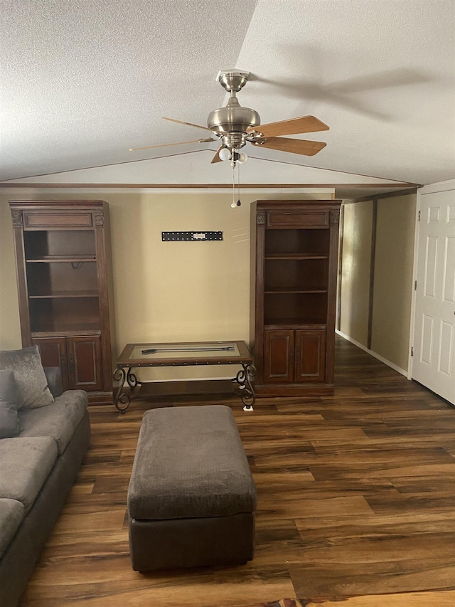 living area featuring a ceiling fan, dark wood-style floors, ornamental molding, vaulted ceiling, and a textured ceiling