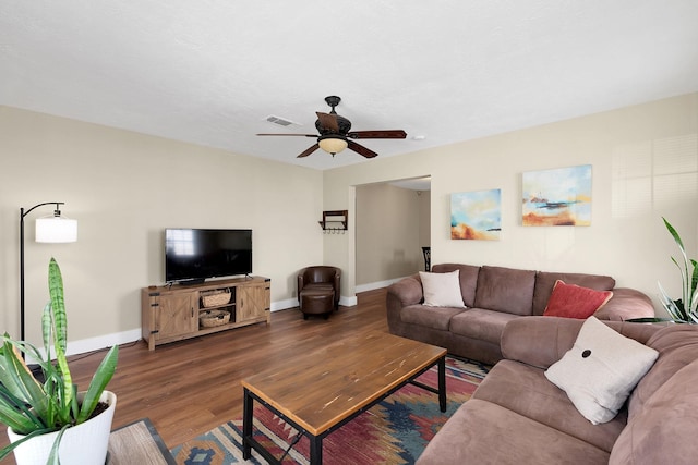 living room with ceiling fan, visible vents, baseboards, and wood finished floors