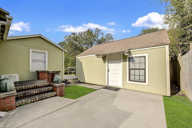 exterior space featuring a patio area, an outdoor structure, fence, and roof with shingles